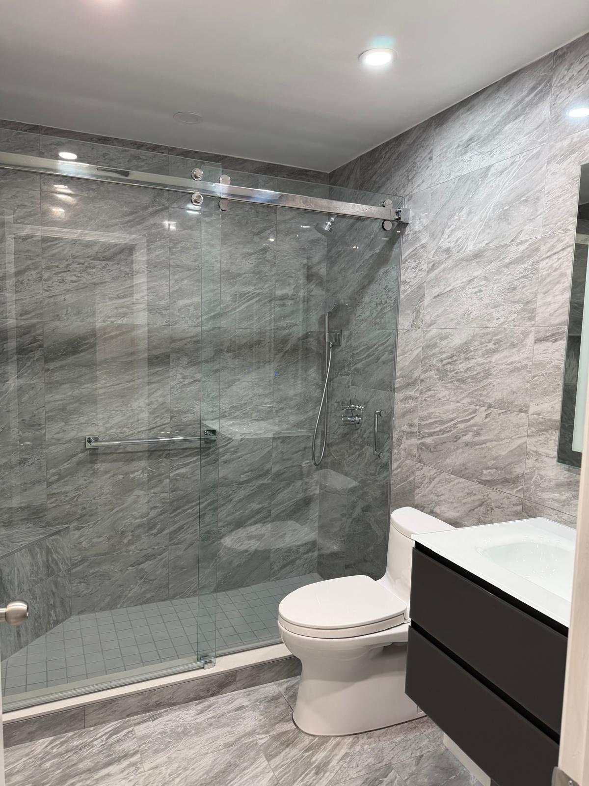 Frameless sliding glass shower with grey marble porcelain tile
