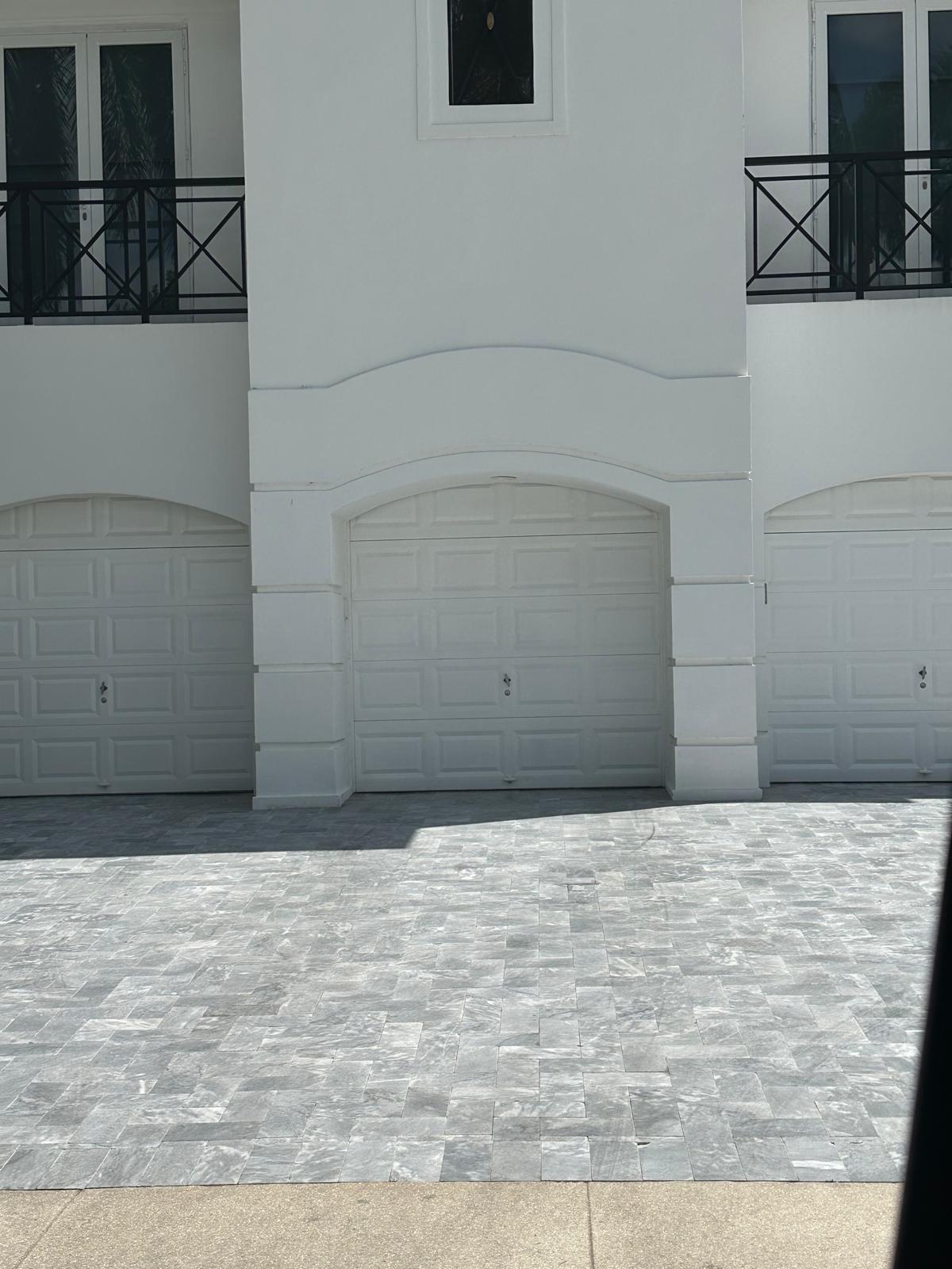 Renovated exterior facade with refinished garage doors and marble pavers