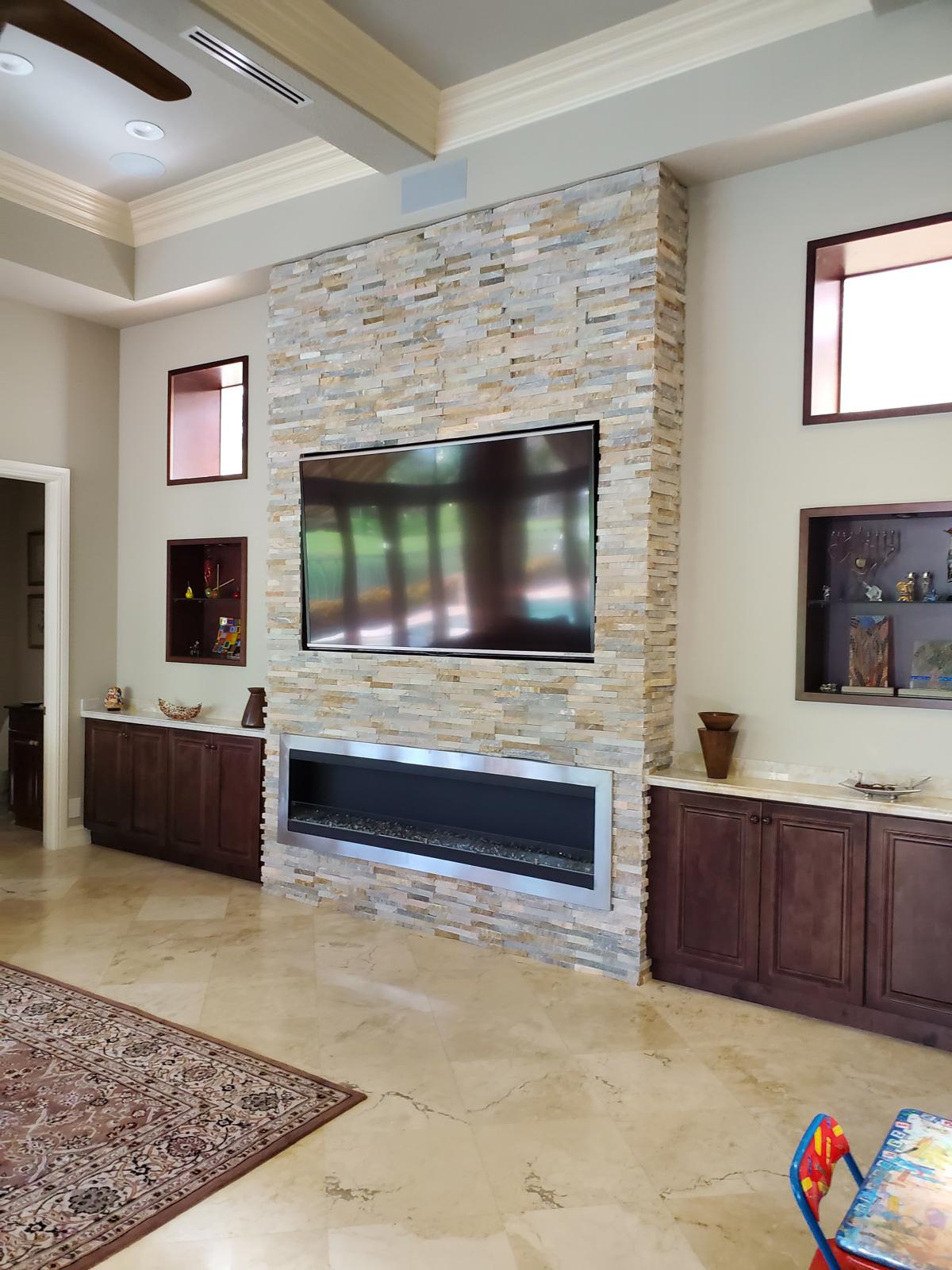 Stone feature wall with mounted TV, linear fireplace and custom wood cabinetry
