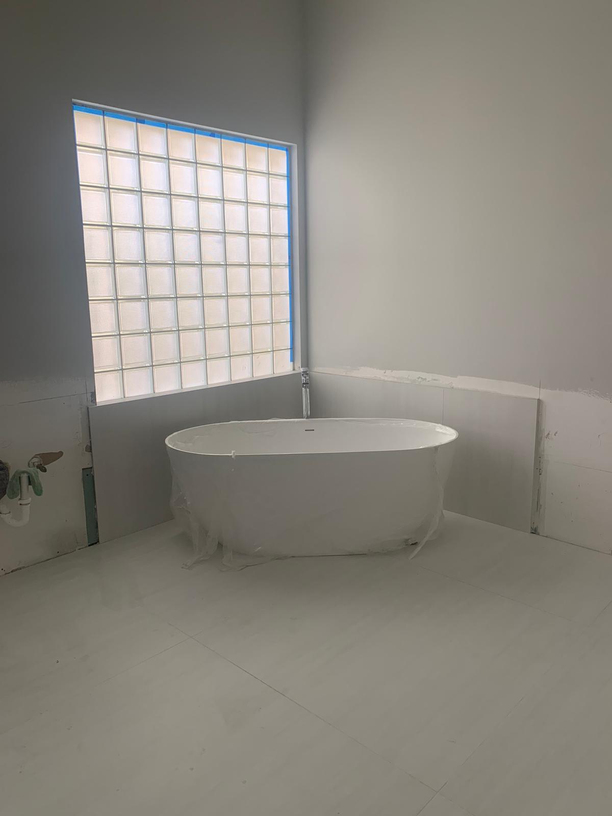 Luxury freestanding soaking tub under a glass block window