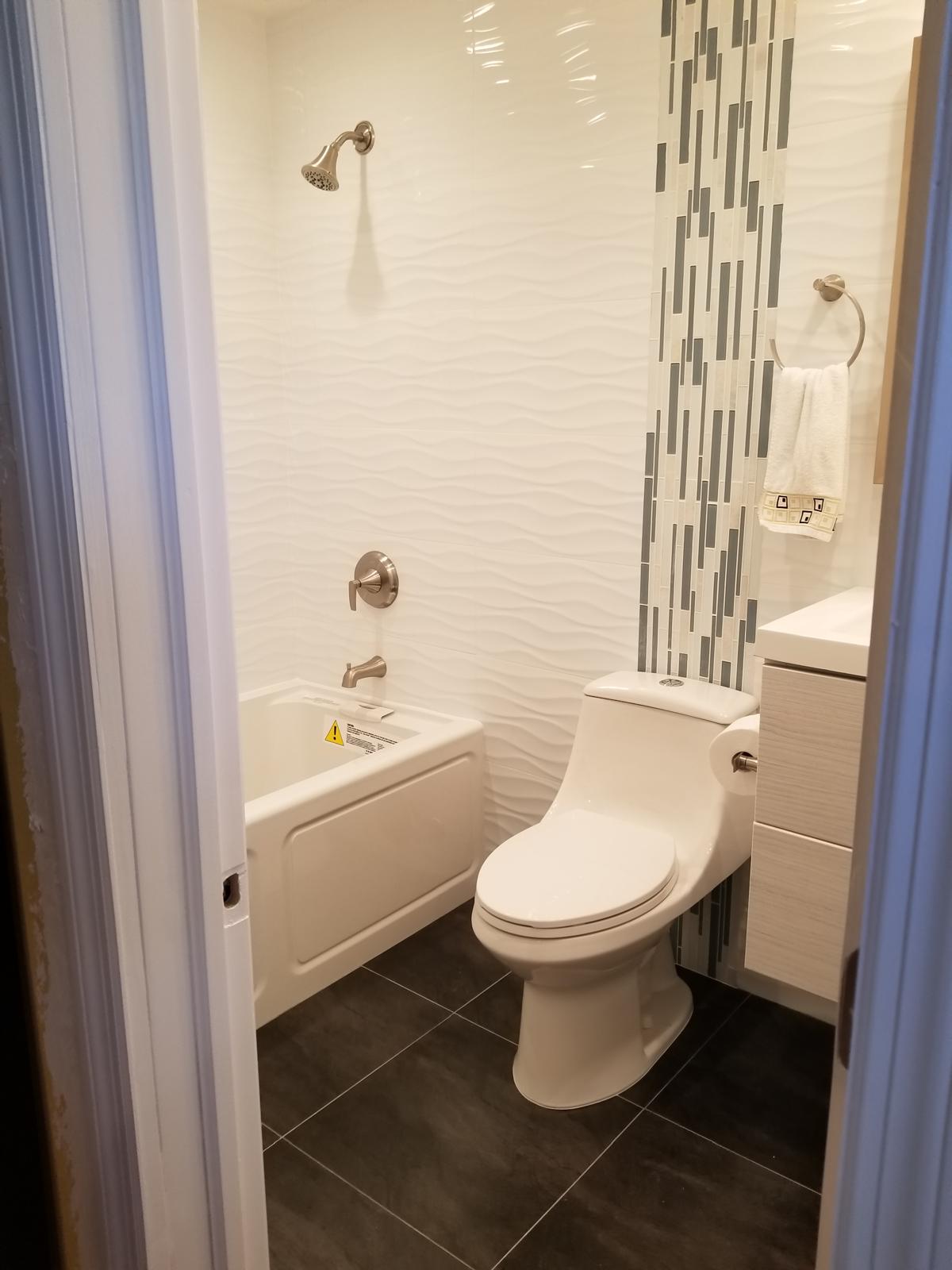 Wave-textured tile tub and shower with mosaic accent column
