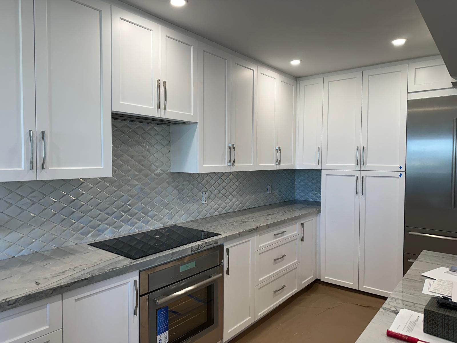 White shaker kitchen with diamond glass tile backsplash and quartzite counters
