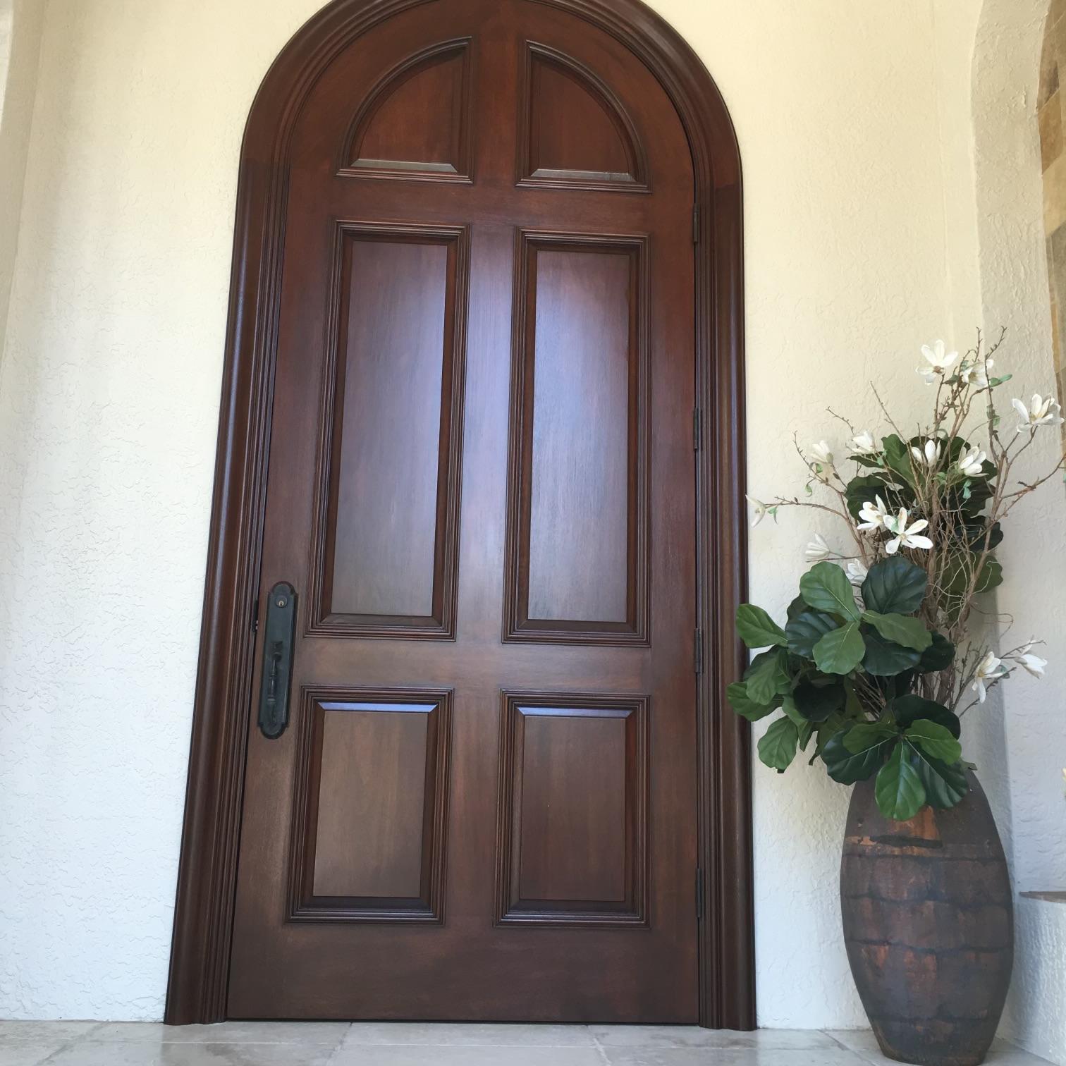 Refinished four-panel arched mahogany entry door with deep varnish