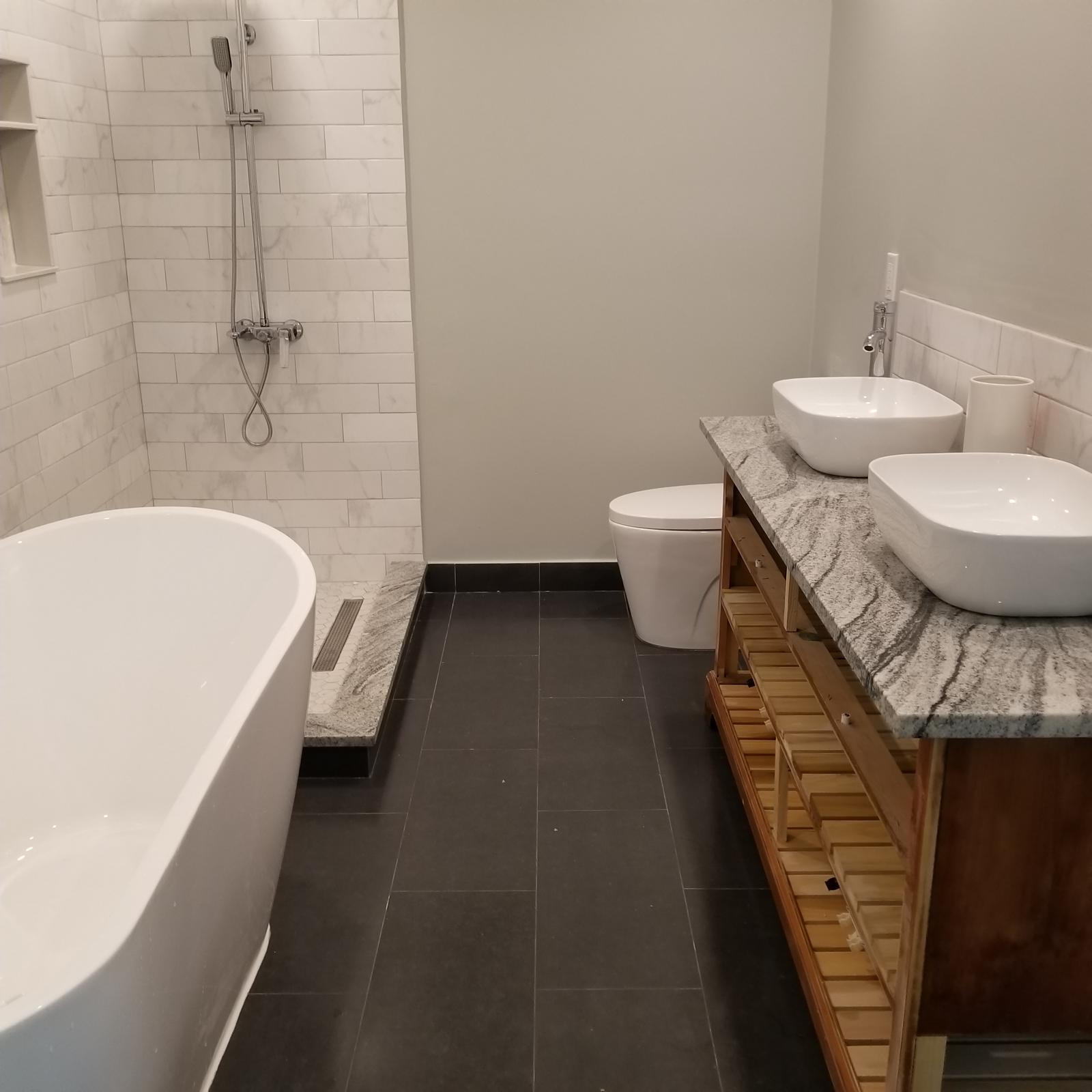 Freestanding soaking tub beside a marble subway tile shower