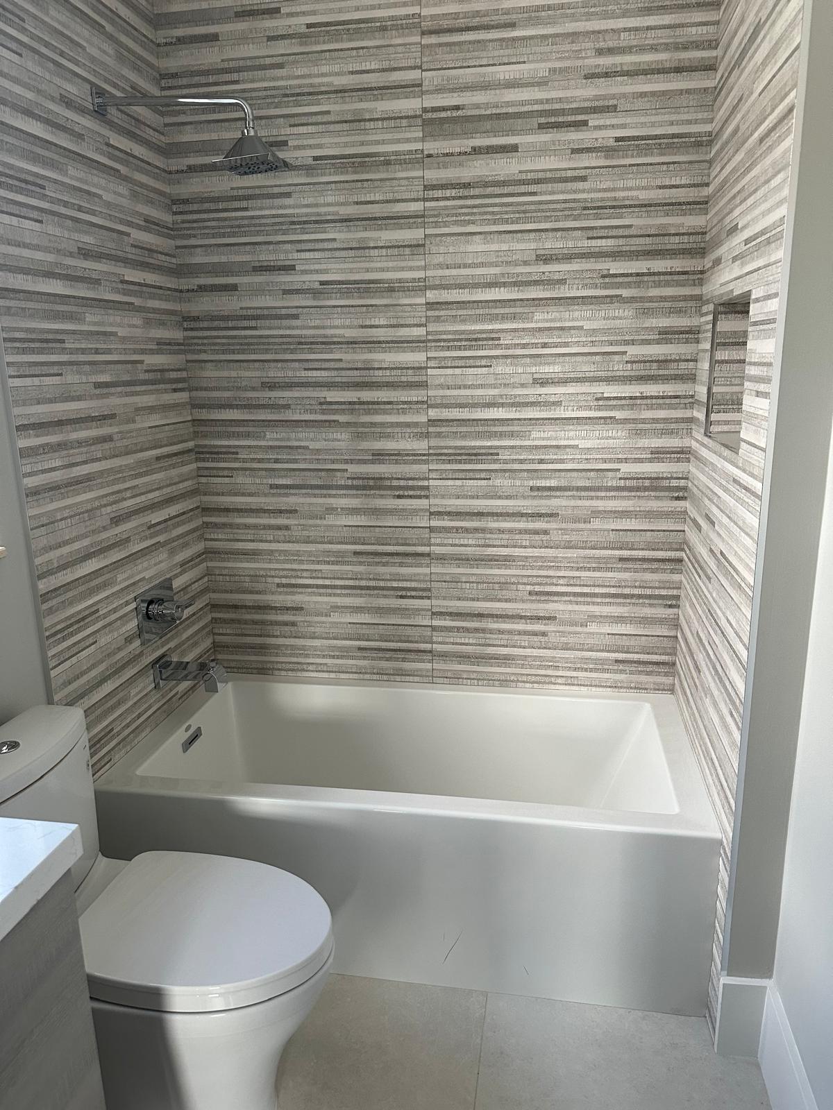 Deep soaking tub with layered stone-look tile surround