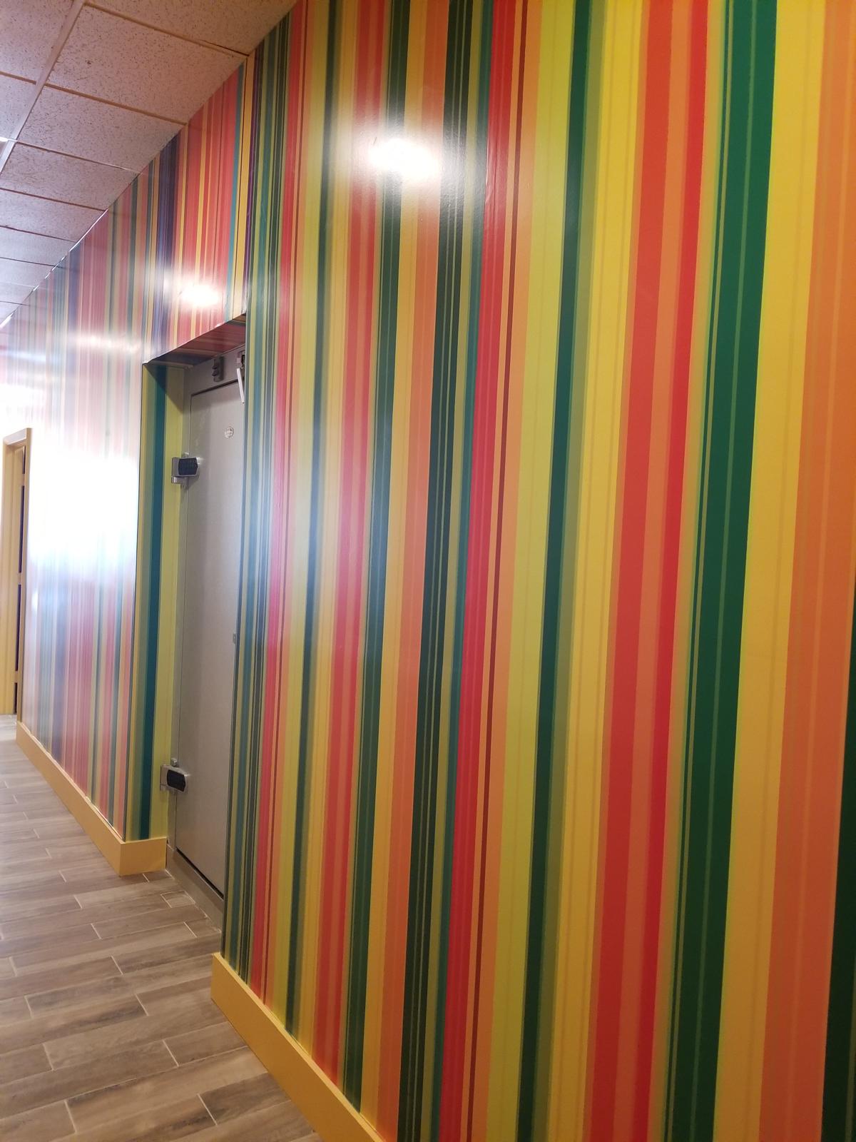 Glossy multicolor striped wallcovering along a finished commercial corridor