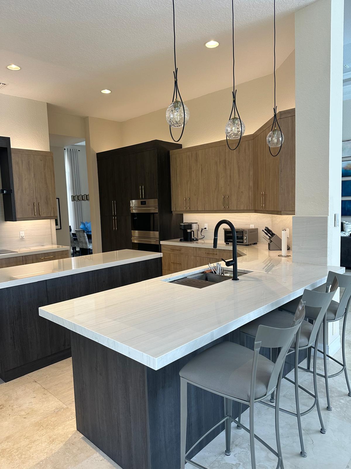 Modern open-concept kitchen with white marble peninsula and glass globe pendants