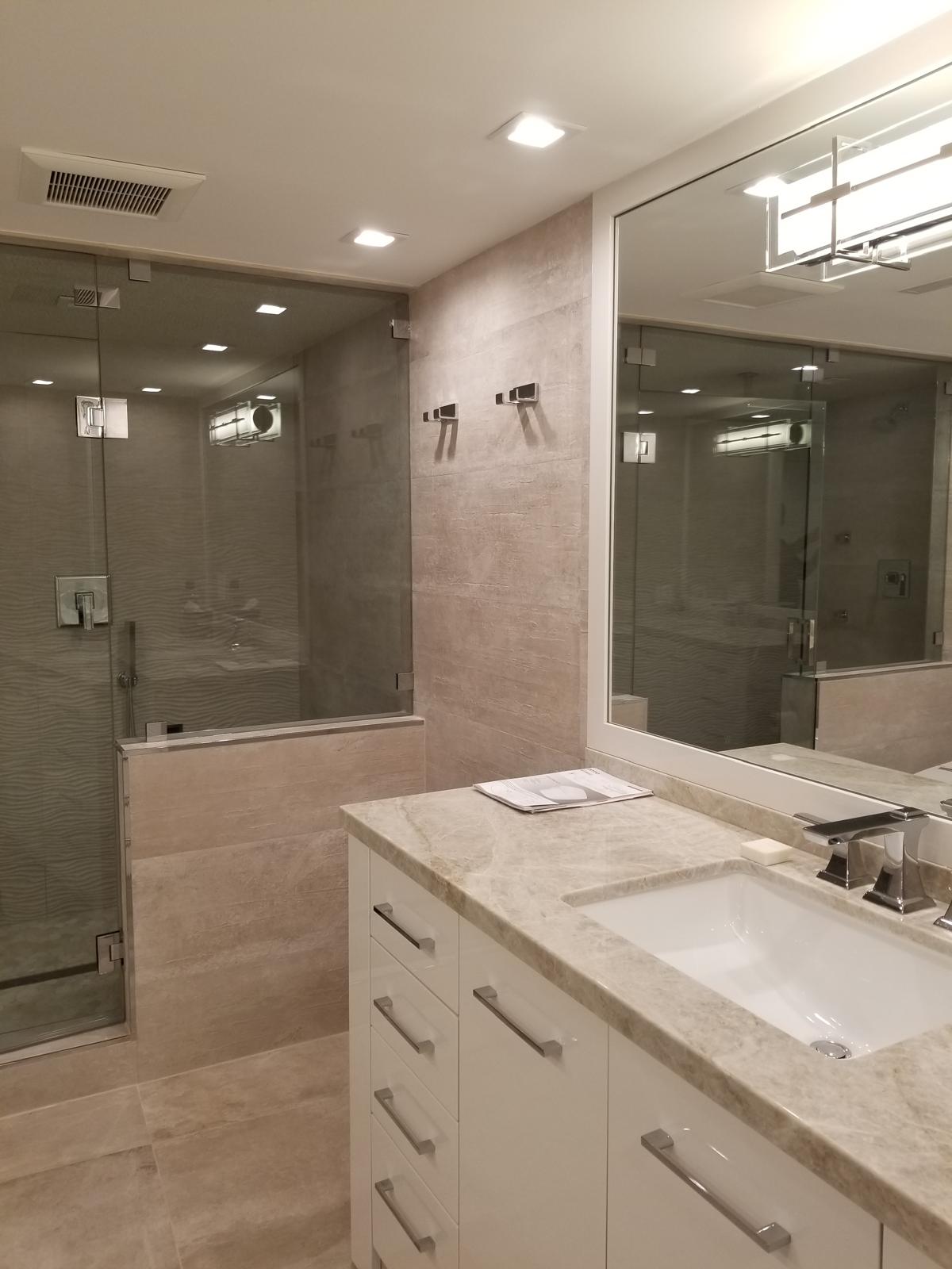 Marble vanity countertop with framed mirror and glass shower