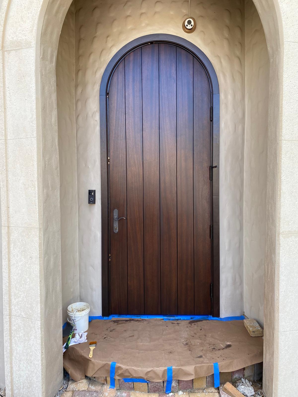 Completed dark-stained arched plank entry door with satin varnish