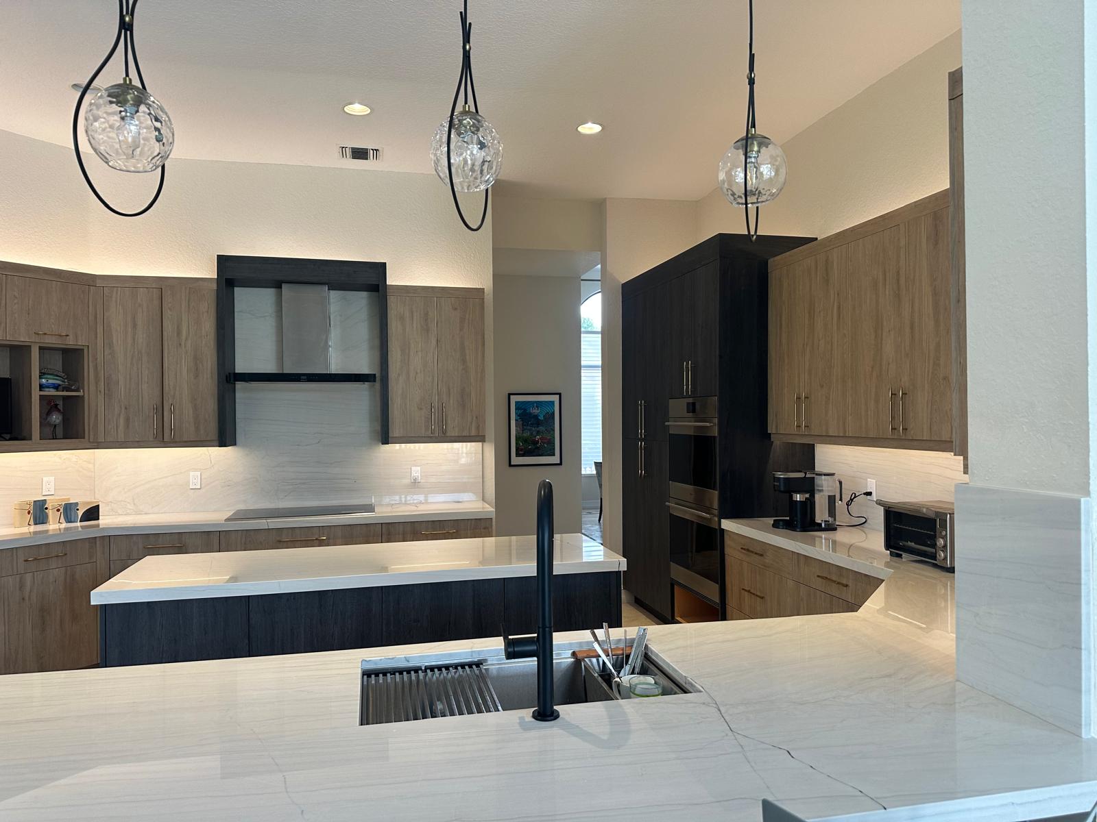Two-tone modern kitchen with quartz island, black fixtures and integrated appliances