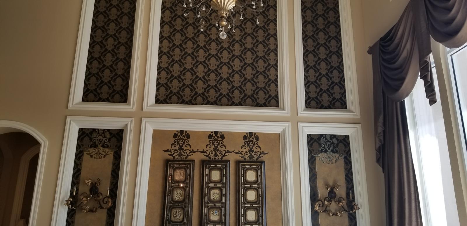 Double-height wall with white boiserie moldings and damask wallcovering panels